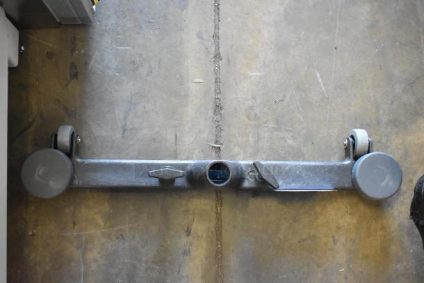 Metallic leveler bar with wheels on each end, featuring two mounting points. Slightly worn condition.