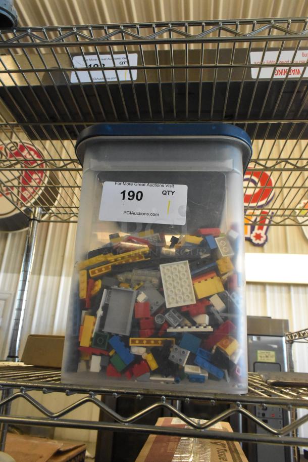 Transparent container filled with assorted Lego pieces in various colors and sizes, labeled "190" for auction.