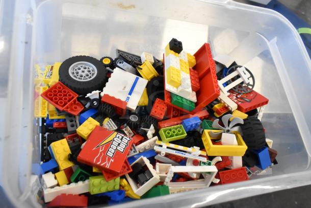 Box of assorted Lego pieces, including wheels, blocks, and printed tiles, in various colors and shapes, in used condition.