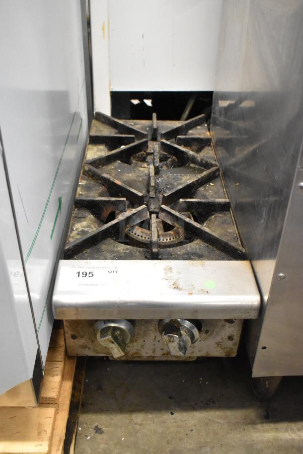 Stainless steel commercial countertop gas-powered 2 burner range with visible wear, featuring two dials and cast iron grates.