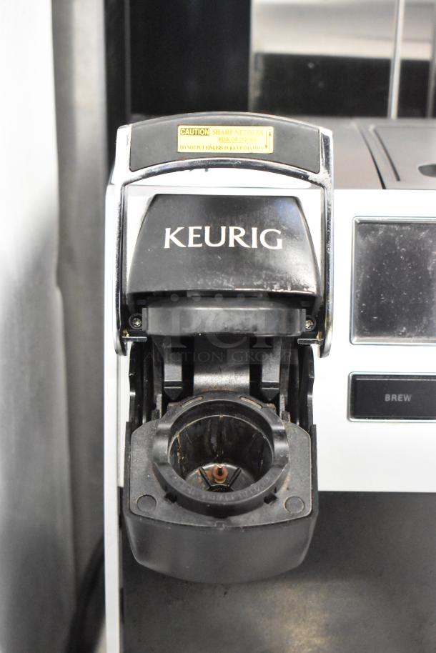 Keurig K150 coffee maker, open K-Cup chamber, caution label visible, countertop model, gently used condition.