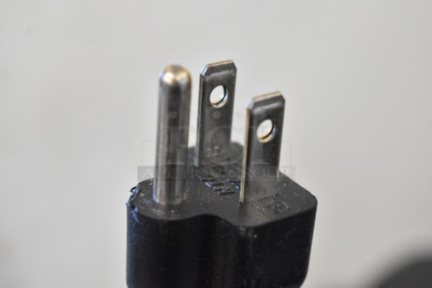Close-up image of a three-pronged plug for a Keurig K150 Coffee Maker, showing metal prongs and black plastic body.
