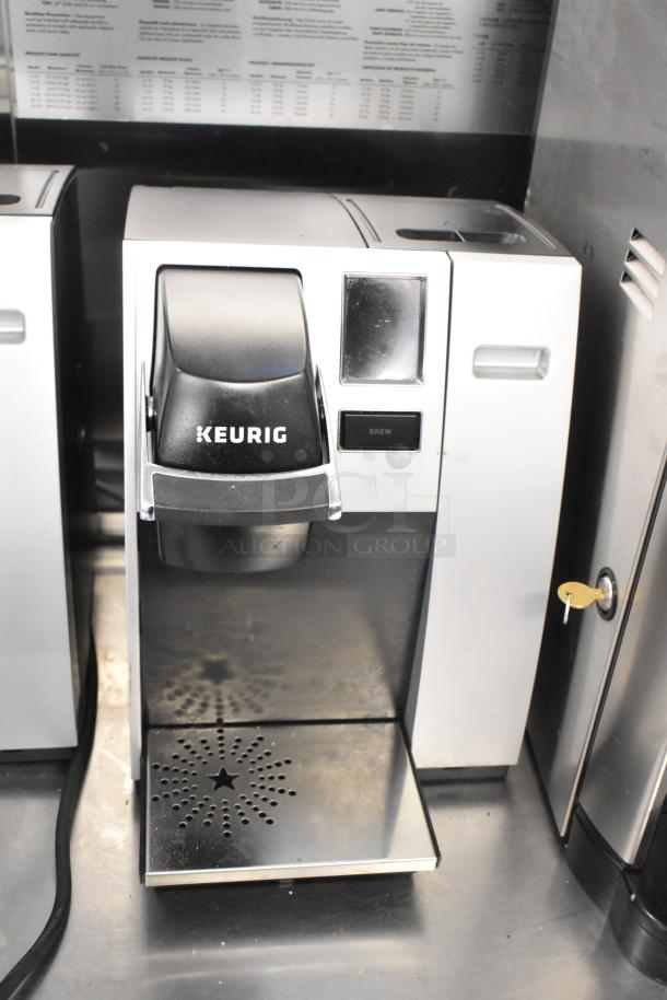 2 Keurig K150 countertop single cup coffee makers, stainless steel finish, with visible Keurig logo and brew button.