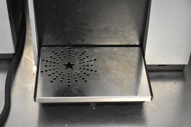 Keurig K150 coffee maker drip tray with star pattern design in used condition, showing metal surface and wire.