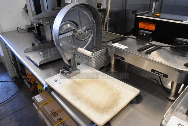 Nemco metal countertop vegetable slicer with white handle mounted on cutting board, shows wear, appears functional.