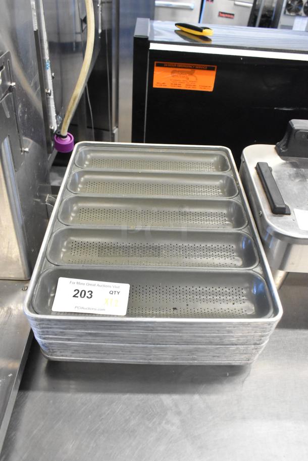Stack of 12 metal 5-loaf perforated baking pans in good condition. Labeled "203 QTY X12" by PCIAuctions.com.