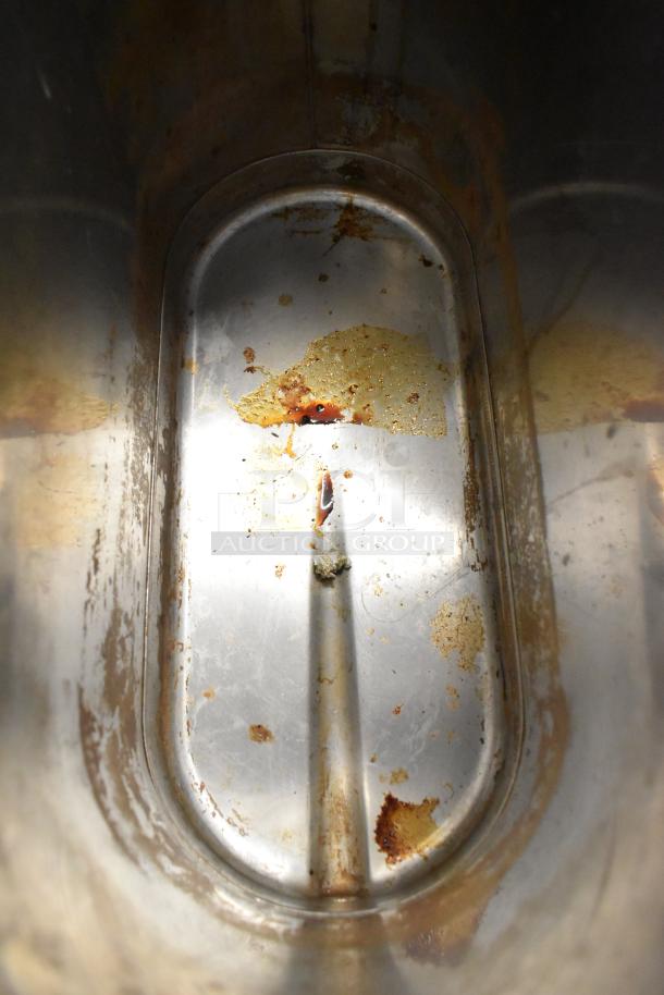 Interior view of a used Bunn TDO-N-3.5 stainless steel iced tea dispenser with visible wear and stains inside.
