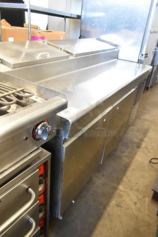 Stainless steel pizza prep table on commercial casters, 115 volts, 1 phase, features refrigeration and storage space, good condition.