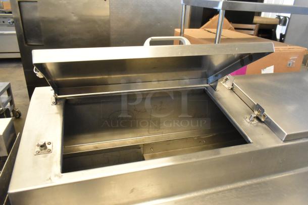 Stainless steel commercial pizza prep table with open lid, showing internal compartment. Features commercial casters, 115 volts, 1 phase.