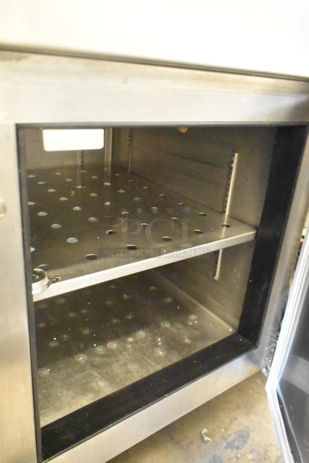 Stainless steel commercial pizza prep table on casters, 115 volts, 1 phase. Features shelves and perforated interior.