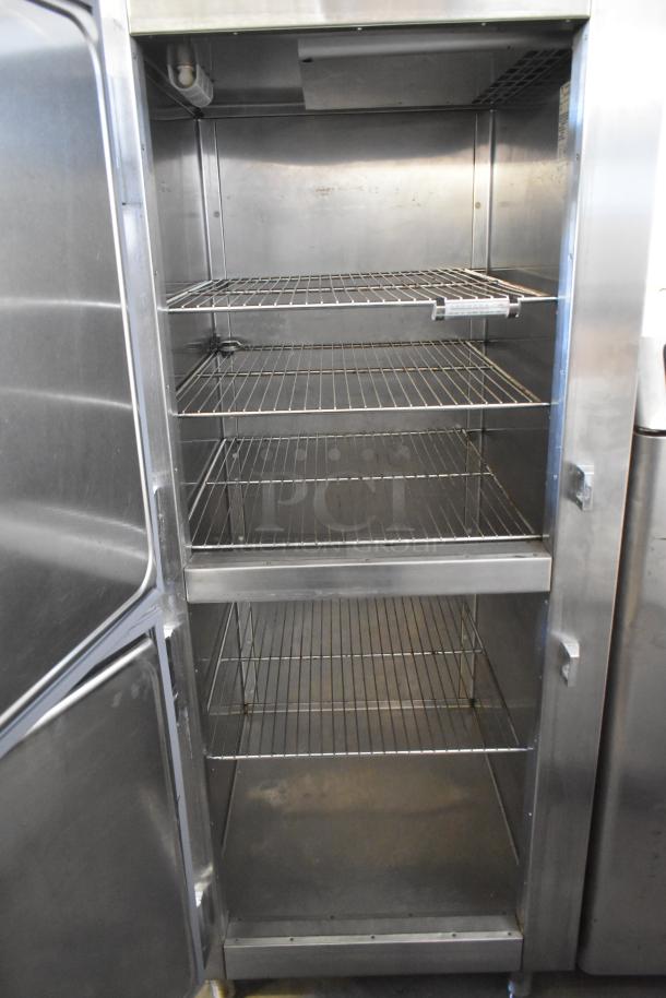 Traulsen RHT132WREHHS stainless steel fridge, 2 half-size doors, commercial casters, 115V, 1 phase, visible shelves.