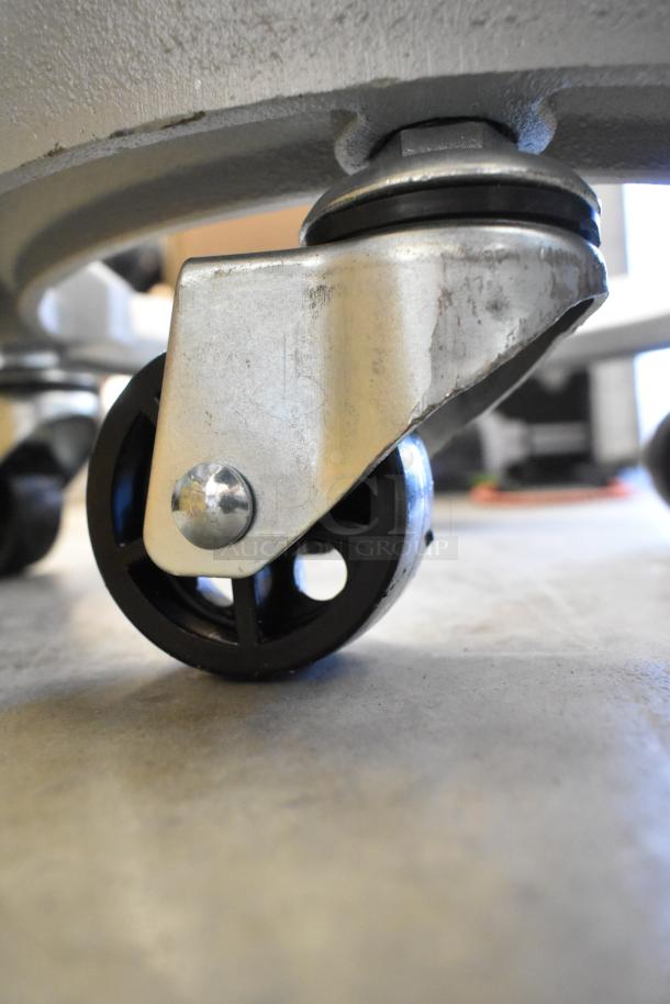 Metal bowl dolly with commercial caster wheels, showcasing slight scratches. Brand new, durable construction.