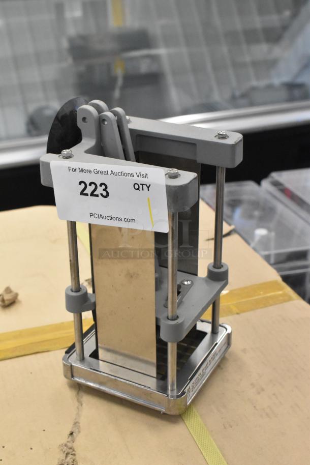 Metal countertop vegetable cutter with vertical blade assembly, sturdy metal frame, and grid base on display. Marked item 223.