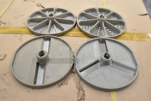 Set of 4 metal food processor blades: 2 slicing, 2 grating. Visible wear, stored on cardboard. Suitable for enhancing kitchen efficiency.