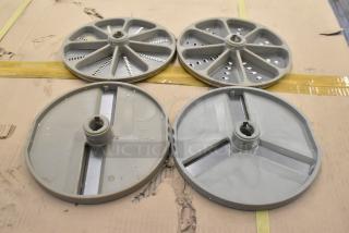 Set of 4 metal food processor blades: 2 slicing, 2 grating. Visible wear, stored on cardboard. Suitable for enhancing kitchen efficiency.