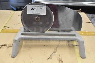 Metal countertop manual meat slicer with circular blade, mounted on a sturdy base. Some wear visible. Auction tag labeled "228".