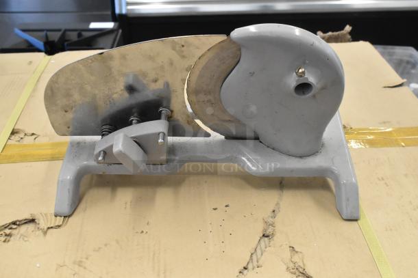 Metal countertop manual meat slicer in used condition, featuring a circular blade and sturdy base, ideal for kitchen use.