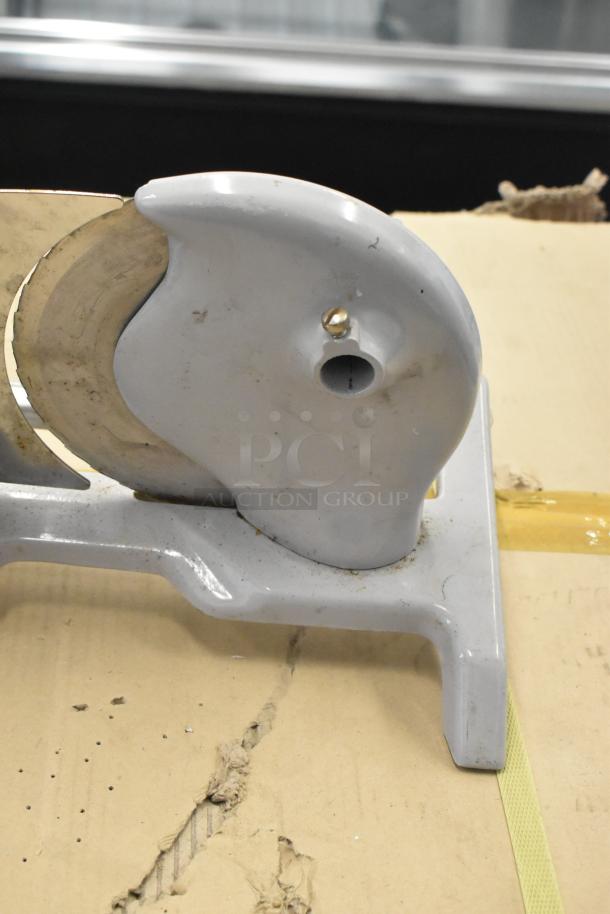 Metal countertop manual meat slicer, featuring a circular blade and sturdy base, moderate wear visible, ideal for kitchens.