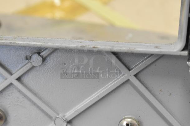 Metal manual meat slicer detail, showing number "460910" on base with visible screws, indicating sturdy construction.