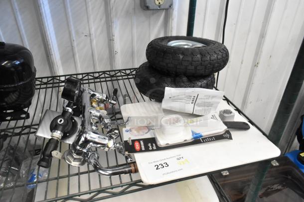 Various items including two black wheels, a chrome faucet, and OXO garlic slicer on a metal shelf.