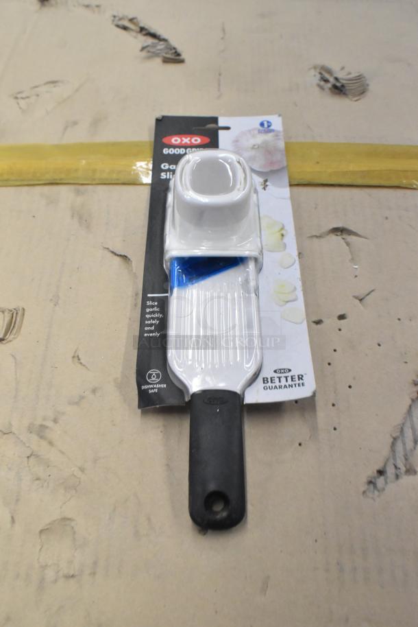 Oxo garlic slicer with dishwasher-safe label, in original packaging, featuring a comfortable grip handle.