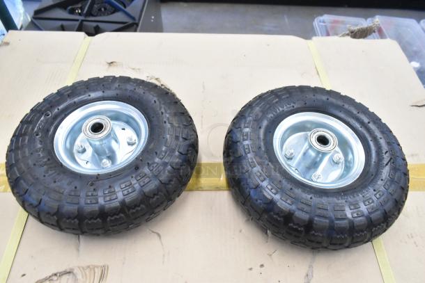 Two sturdy rubber wheels with metal hubs on a cardboard surface, suitable for carts or equipment. Great condition.