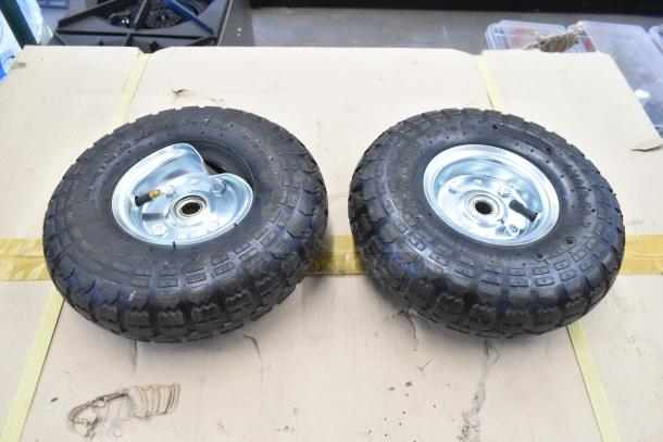 Two sturdy black rubber wheels with steel hubs, suitable for carts or equipment, in very good condition.