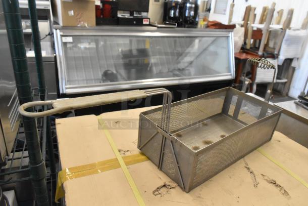 Two metal fry baskets with perforated sides and long handles, showing signs of use, ideal for commercial frying.