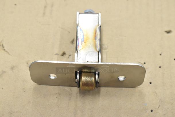 Metal bracket with two mounting holes shown on cardboard surface; likely a component part. Scratched finish.