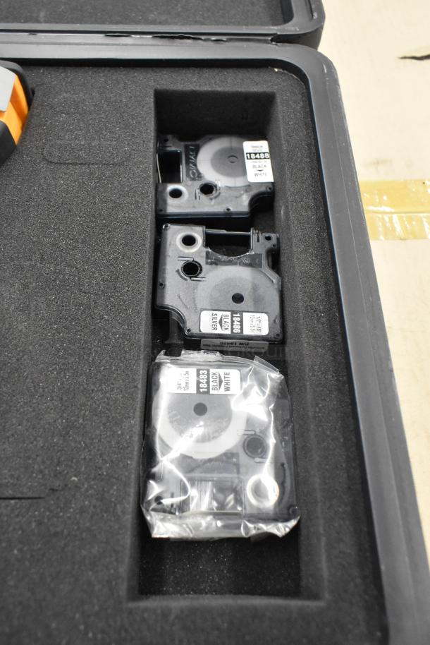 Dymo RhinoPro 5000 Label Printer in a hard case with multiple label cartridges. Labels marked "Black on White" and "Black on Silver."
