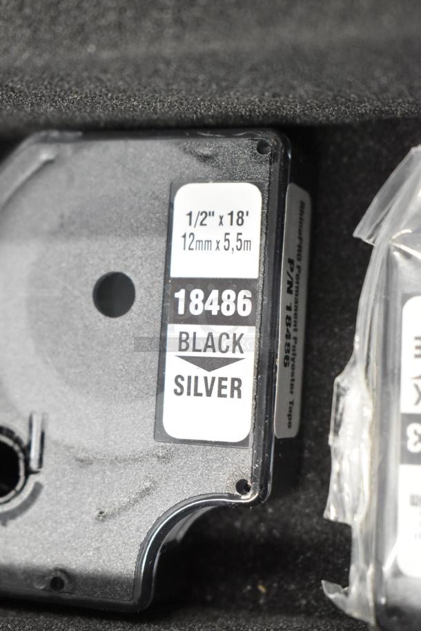 Dymo RhinoPro 5000 label printer tape, black on silver, 1/2" x 18', in hard case; part number 18486 visible.