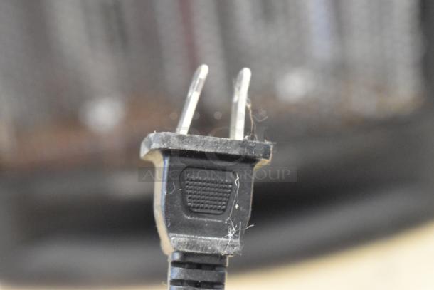 Close-up image of a black plug from a Living Zone BFGF-15D Quartz Heater, 115 Volts, 1 Phase. Dust visible on plug.