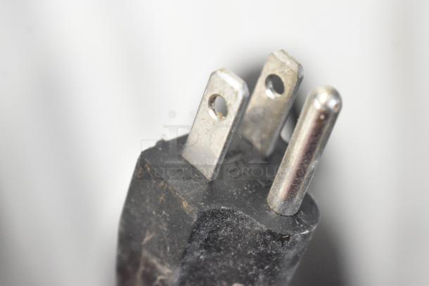 Close-up of a three-prong electrical plug for Avantco 177W62BLK Two-Head Food Warmer, showcasing metal prongs and black casing.