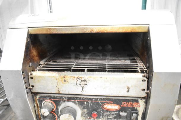 Hatco TQ-800HBA metal commercial toaster oven, showing wear and rust. Features conveyor belt and control dials. 208V, 1 Phase.