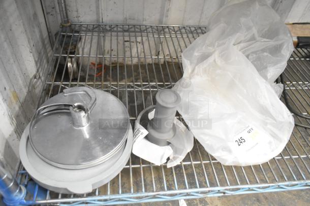S blade and slicing blade for food processor, metal finish, on wire shelf. Item tag shows "245 QTY 4X."