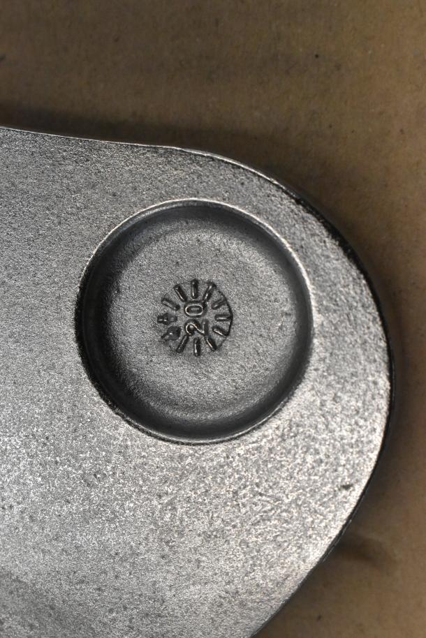 Close-up of a metal food processor blade featuring engraved markings, displaying its finish and texture for auction.