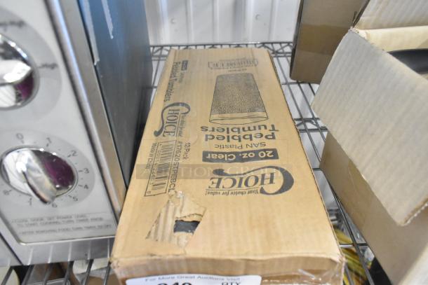 Cardboard box labeled "Choice 20 oz. Clear Plastic Pebbled Tumblers," unopened with a minor tear visible on the side.