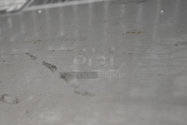 Blurry image showing scratches and dirt particles on a metal surface. No visible labels or markings.