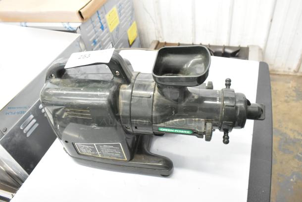 Green Power countertop juice extractor, black, used condition, visible label with specifications. Side view on countertop.