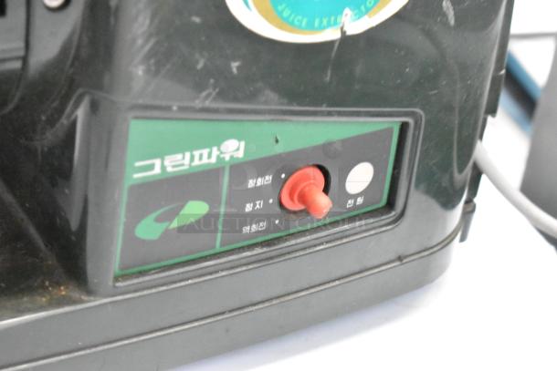 Countertop juice extractor, black casing, visible control panel with red switch, Korean labels, minor scratches.