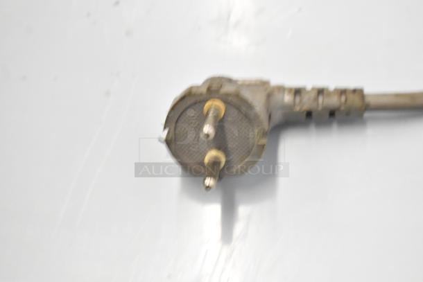 Close-up of a power plug, part of a countertop juice extractor, showing wear and surface marks.