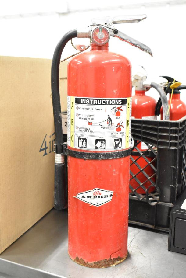Red Amerex fire extinguisher with visible instruction label. Some wear at the base. Includes four additional extinguishers. Pick-up only.