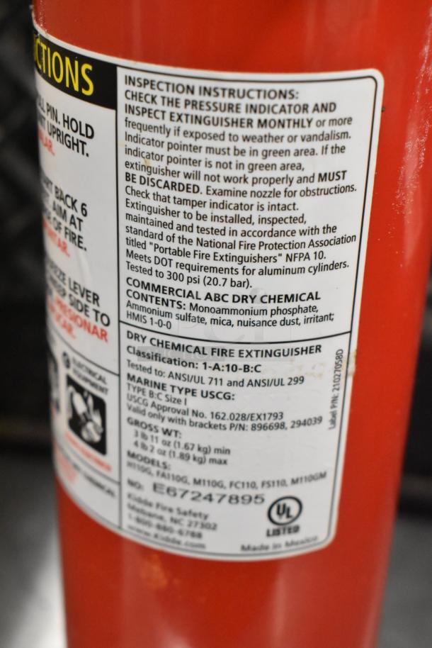 Close-up of a fire extinguisher label detailing inspection instructions, classification as ABC type, and model information.
