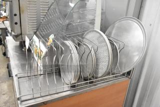 Metal countertop pizza pie pan rack with metal round pizza pans and pizza screens displayed, ideal for baking setup.