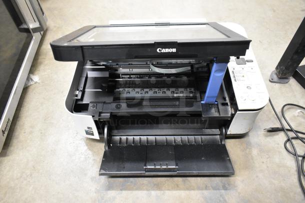 Canon K10339 printer with open paper tray and visible control panel, showing signs of wear. Power cord connected.