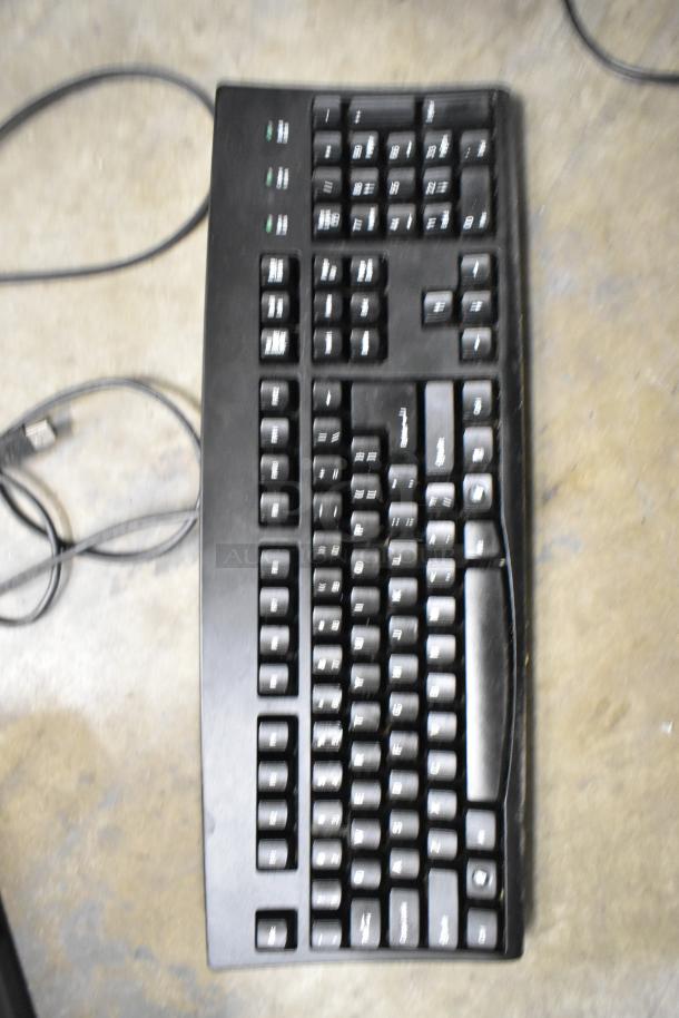 Black computer keyboard with visible numeric keypad and connection cable, part of POS system setup.