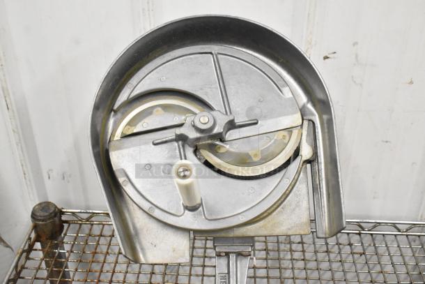 Nemco metal countertop vegetable slicer, featuring a round blade mechanism, mounted on a wire rack, in used condition.