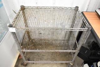 Chrome finish 3 tier wire cart with commercial casters, showing signs of wear. Equipped with a visible quantity label.