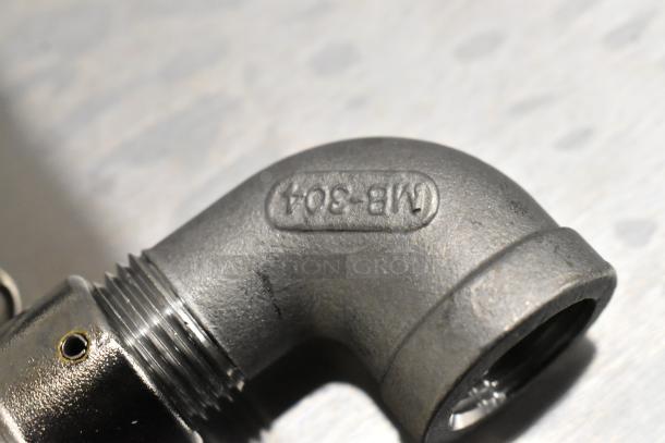 Close-up of metallic elbow joint with stamped marking "MB-804" on a threaded pipe fitting, showcasing detail and condition.
