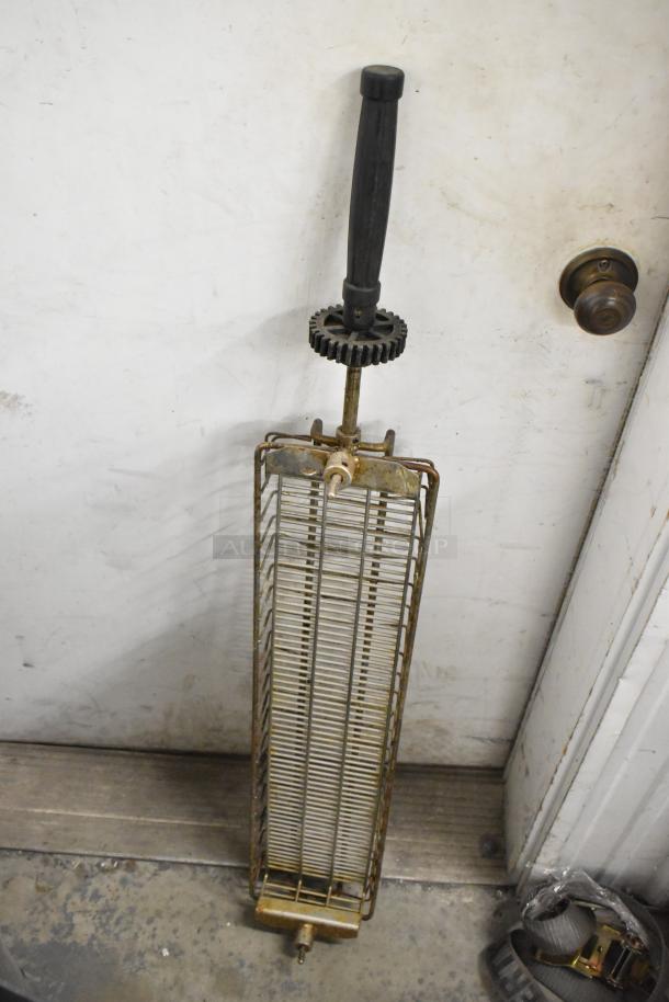 12 metal rotisserie basket skewers in gray poly trash can, features black handle and gear mechanism, used condition.